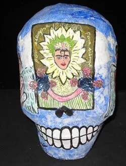 Skull painted with blue and a portrait of artist Frida Kahlo in a sunflower with a green and white flower headdress.